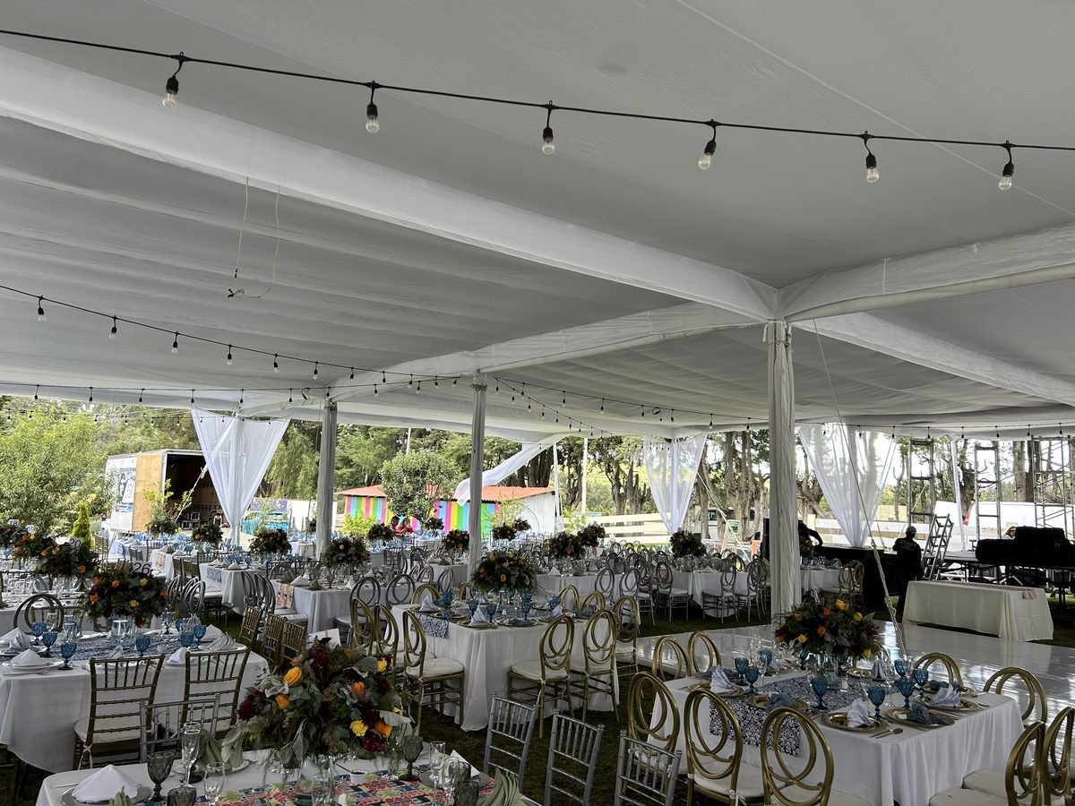 Mesas con manteles blancos bajo una carpa para una boda