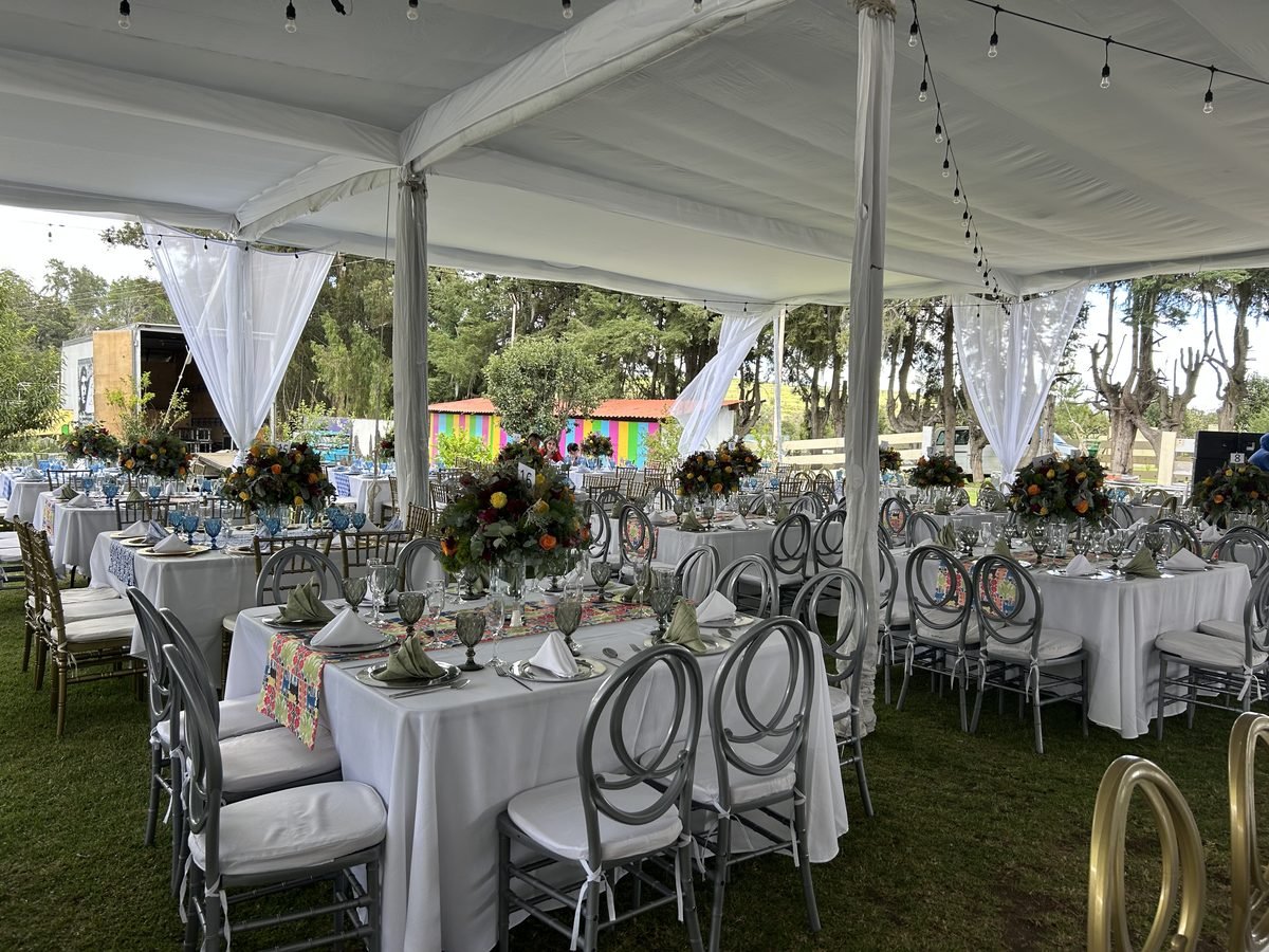 Mesas largas con centros de flores bajo una carpa, para una boda