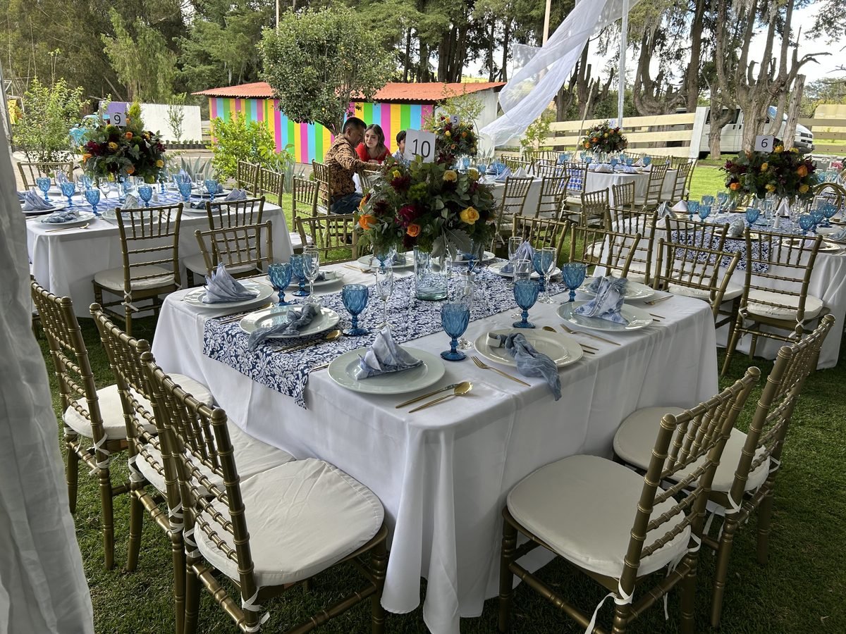 Mesas con mantelería azul y centros de flores para una boda