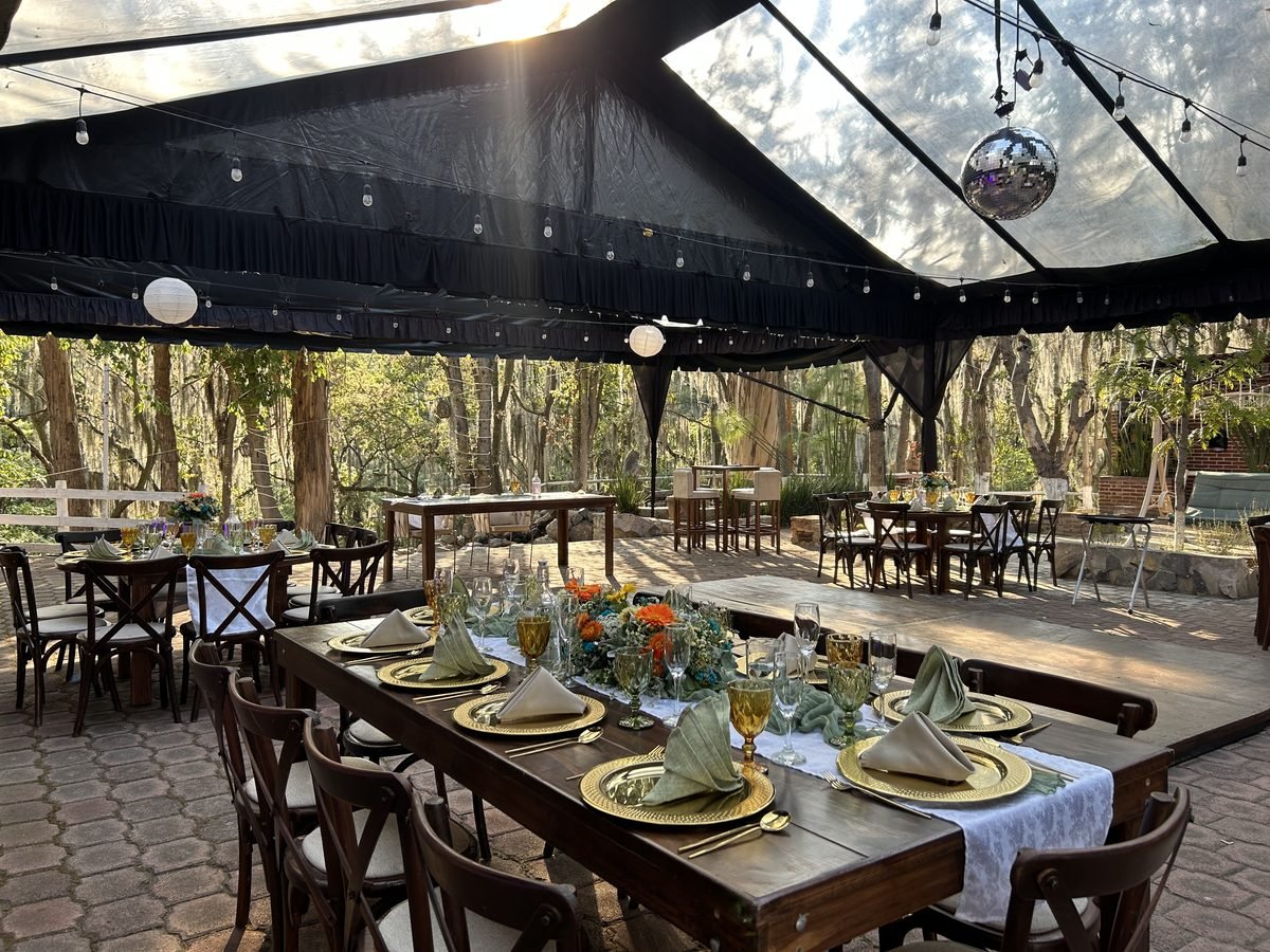 Carpa decorada con luces y pista de baile, entre los árboles
